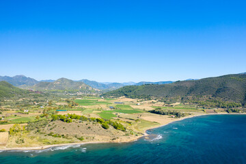 The arid rocky coast and its green countryside, in Europe, in Greece, in Aetolia Acarnania, towards Patras, by the Ionian Sea, in summer, on a sunny day.