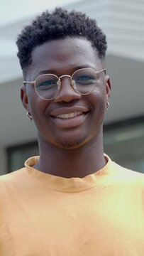 Portrait of a young African American man looking seriously at camera and then laughing in a city