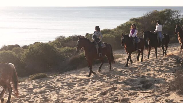 young women riding horses near the sea