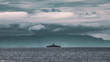 Dramatic clouds before the storm. Ship against the background of mountains in the Trondheim fjord.