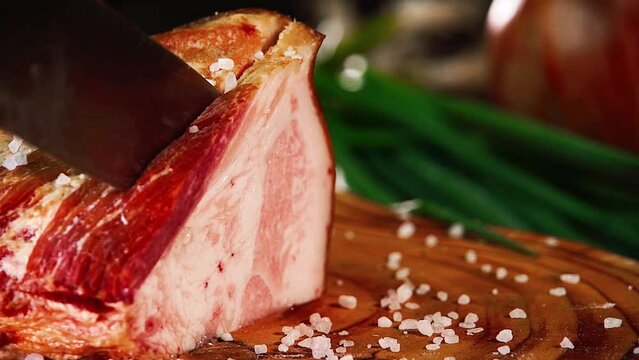 Slicing salo on a wooden board with onions and salt