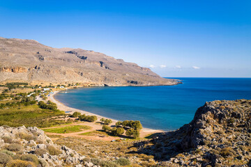 The sandy beach at the foot of the arid mountains , in Europe, Greece, Crete, Kato Zakros, By the Mediterranean Sea, in summer, on a sunny day.