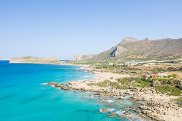 The sandy beach at the foot of the rocky cliffs in the arid countryside , in Europe, Greece, Crete, towards Kissamos, towards Chania, By the Mediterranean Sea, in summer, on a sunny day.