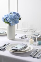 Beautiful table setting with card and floral decor indoors