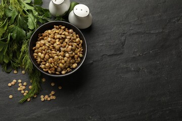 Delicious lentils in bowl with parsley and dill on grey textured table, flat lay. Space for text