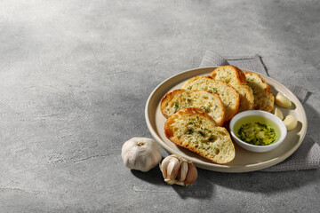 Tasty baguette with garlic and dill served on grey textured table, space for text