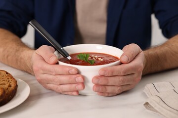 Man with delicious tomato soup at light table, closeup