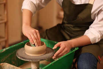 Clay crafting. Woman making bowl on potter's wheel indoors, closeup - obrazy, fototapety, plakaty