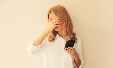 Desperate upset crying young woman with headache holding mobile phone touching her head and...