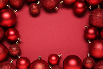 Frame of beautiful Christmas balls on red background, top view. Space for text