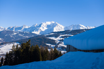A wooden chalet facing the Mont Blanc massif in Europe, France, Rhone Alpes, Savoie, Alps, in winter, on a sunny day.