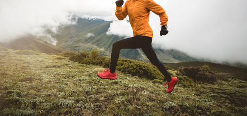 Woman trail runner cross country running at high altitude mountain peak