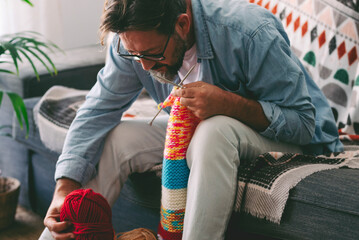 One man at home doing knit activity alone sitting on the sofa. Mature male people love knitting...