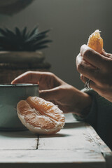 Close up of people in healthy eating concept lifestyle. Hands of a woman with orange fruit and herbal tea for diet of health purpose. Relax leisure activity at home with light breakfast. Vitamins - obrazy, fototapety, plakaty