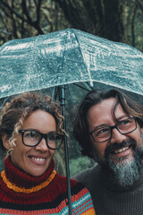 Relationship and love couple under the rain smiling and enjoying outdoor leisure activity in rainy...