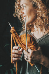 Side portrait of woman smiling and enjoying knit wool work at home alone. Middle age lady in knitting leisure hobby activity. People and time in the house. Concept of single lifestyle happy female
