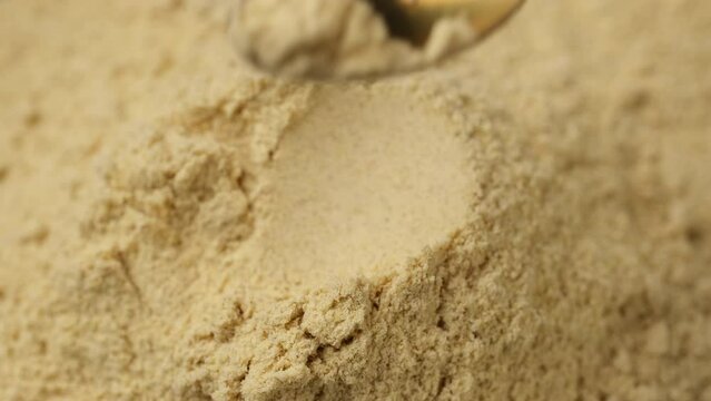 Ground ginger powder in spoon. Condiment or dietary supplement