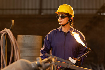 
Female industrial worker working with blow torch in factory