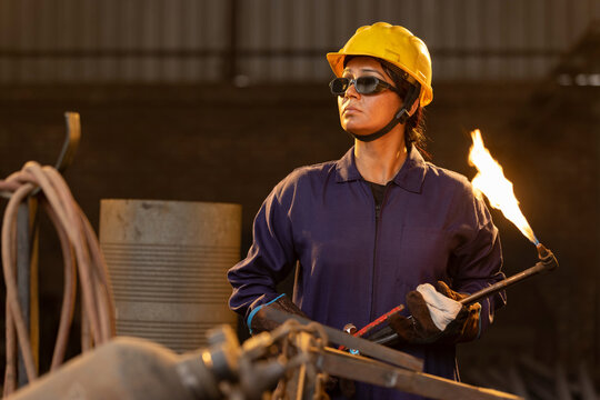 Female industrial worker working with blow torch in factory - Powered by Adobe