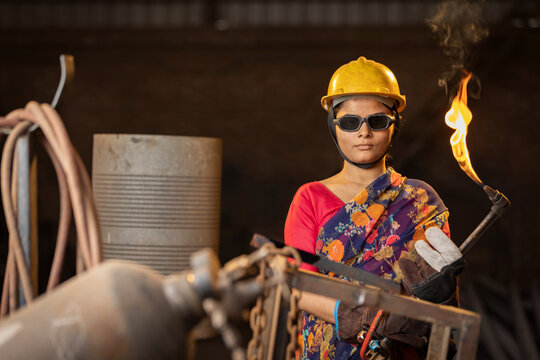 Female industrial worker working with blow torch in factory