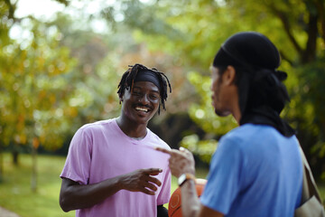 Cheerful Black men hanging out after playing basketball outdoors in local park