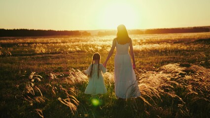 Child and mother choose suitable location for photo shot on field at sunset. Child with mother...