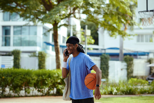 Smiling streetball player calling friend when walking to outdoor court