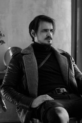 handsome man in black clothes sitting on a chair