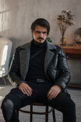 handsome man in black clothes sitting on a chair