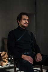 handsome man in black clothes sitting on a chair