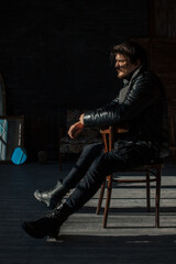 handsome man in black clothes sitting on a chair - obrazy, fototapety, plakaty