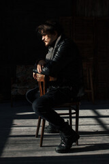 handsome man in black clothes sitting on a chair - obrazy, fototapety, plakaty