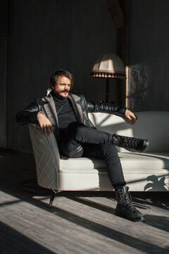 handsome man in black clothes sitting on a chair