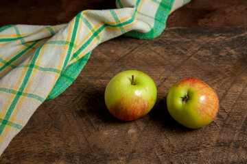 Two green apples on wooden background with green kitchen towel..