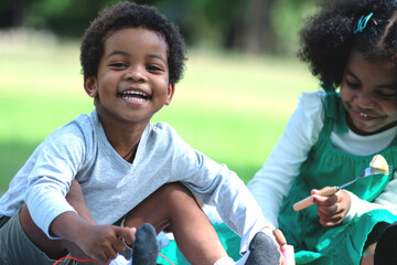 Happy African brothers and sisters Play and eat picnics at the park amidst the bright summer...