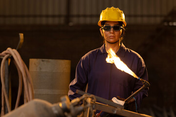 Female industrial worker working with blow torch in factory