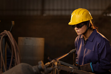Female industrial worker working with blow torch in factory