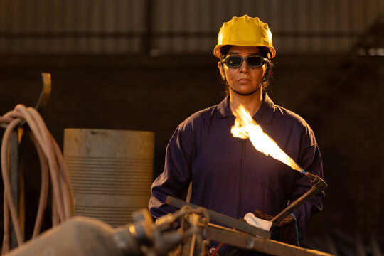 Female industrial worker working with blow torch in factory - Powered by Adobe