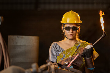 Female industrial worker working with blow torch in factory