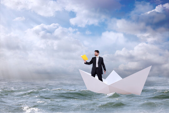 Businessman navigates the open sea atop a paper boat, absorbed in a book.