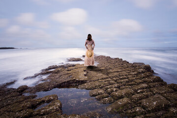 Fototapeta na wymiar Woman graces a rocky perch by the sea
