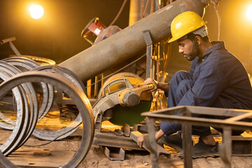 Mechanic using circular saw grinder tool in protective workwear at factory