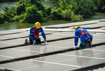 Men technicians carrying photovoltaic solar modules on the factory roof. Engineers in helmets...