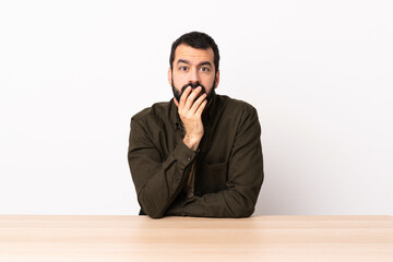 Caucasian man with beard in a table surprised and shocked while looking right.