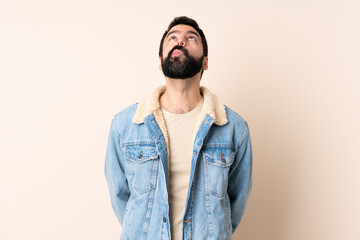 Caucasian man with beard over isolated background and looking up