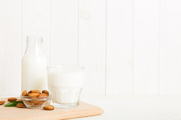 Top view of the almond milk in the glass bottle with almond nuts on the colored table. top view vith copy space
