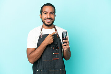 Young hairdresser latin man isolated on blue background pointing to the side to present a product