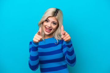 Young Russian woman isolated on blue background surprised and pointing front