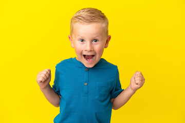 Little Russian boy isolated on yellow background celebrating a victory in winner position