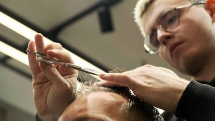 Fashionable hairdresser cuts a man's hair in a barbershop. Men's hairstyle and haircut in the salon. Hair care with a trimmer. Hairdresser makes a haircut in a retro barbershop.